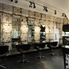 Hair salon with blood-splattered walls and mirrors, empty chairs, and scattered styling tools