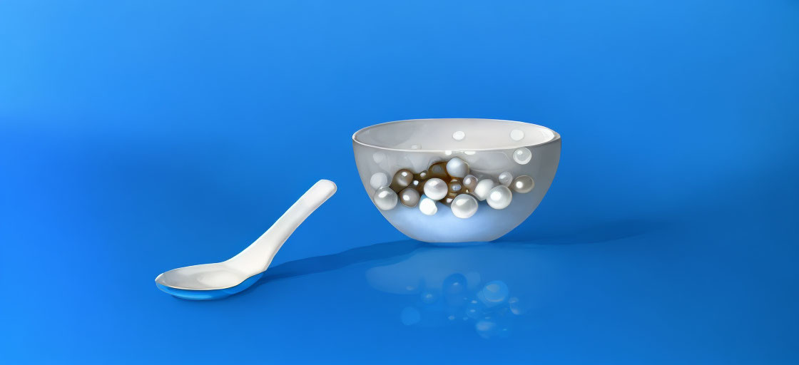 Translucent bowl with spherical objects on blue surface with white spoon