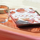 Illustration of glass tumbler, journal, and autumn leaves on leaf-covered surface