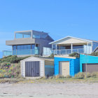 Vibrant beach cabins on white sand with blue skies and wildflowers