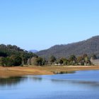 Tranquil autumn landscape with reflective lake, colorful trees, distant mountains, clear sky