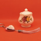 Floral porcelain containers with gold chain pendant on red background