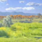 Scenic landscape: green hills, yellow trees, blue sky, mountains