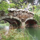 Stone bridge over tranquil pond with autumn trees and misty sunlight