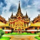 Golden temple with spires in lush greenery under blue sky