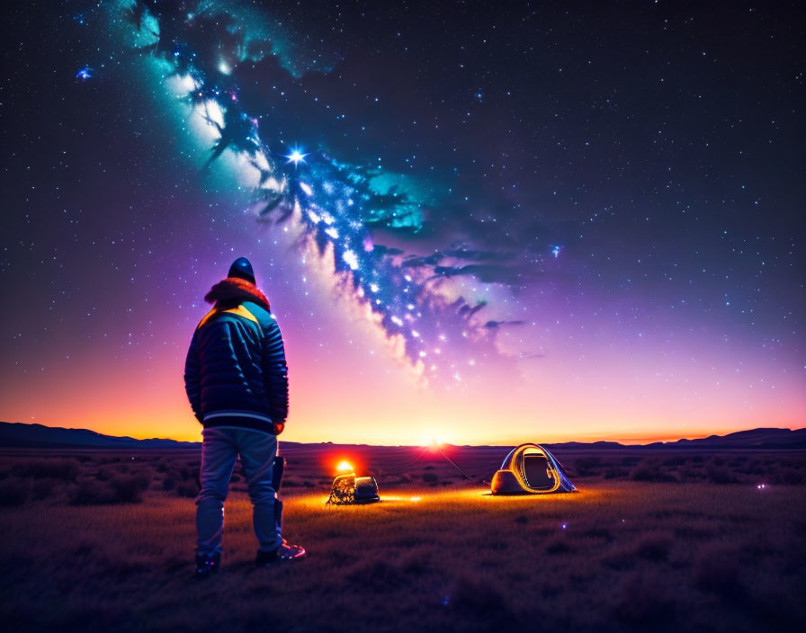 Person admires starry night sky at illuminated campsite