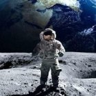 Astronaut in white space suit on moon with Earth rising.