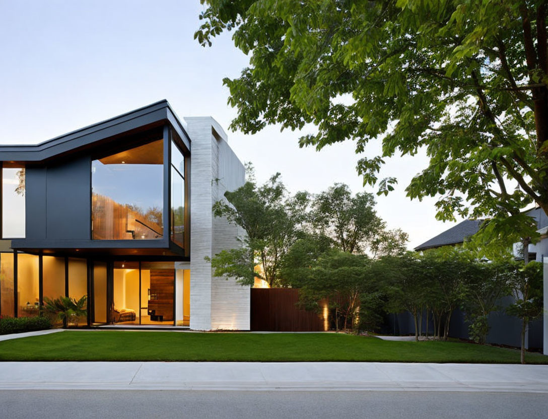 Contemporary two-story house with large glass windows and white concrete & dark metallic panels amidst lush greenery