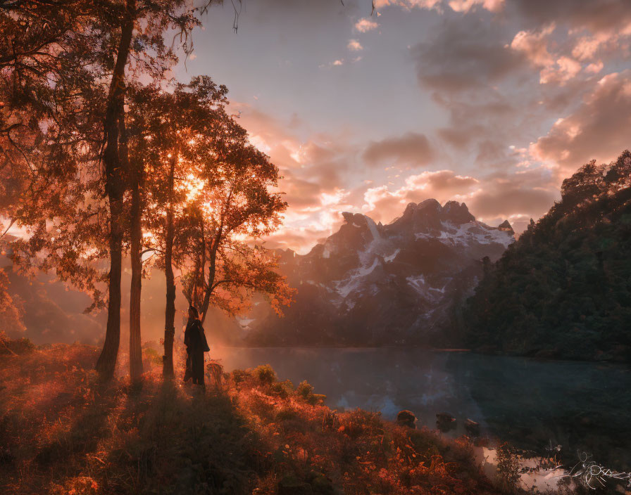 Person standing by lake at sunset with mountains and vibrant sky