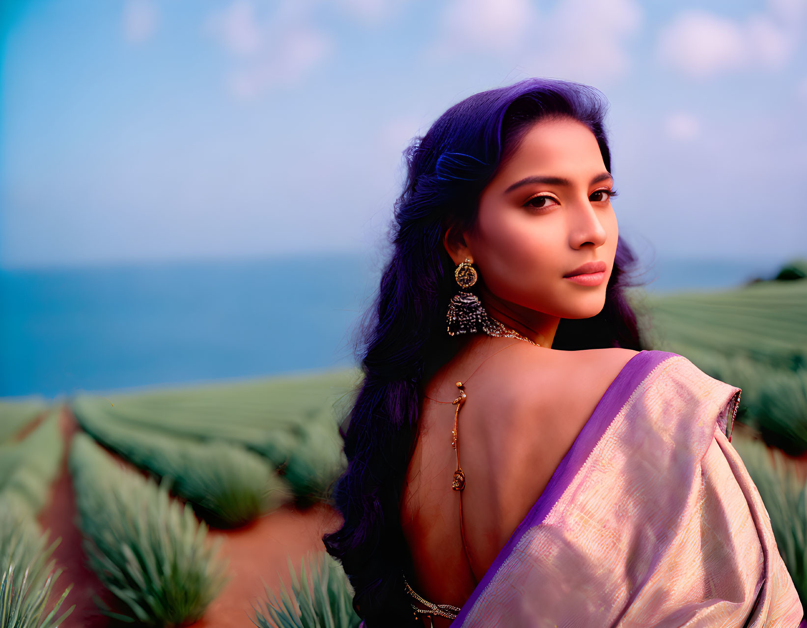 Traditional Attire Woman Poses in Field with Ocean Backdrop