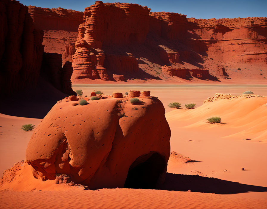 Desert landscape with red sand and rock formation under blue sky