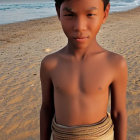 Person in ornate jewelry on sandy beach with ocean waves and rocks in background