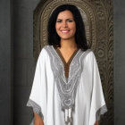 Dark-haired woman in ornate white robe exudes regality in grand hall