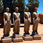 Stylized statues with draped garments in desert landscape