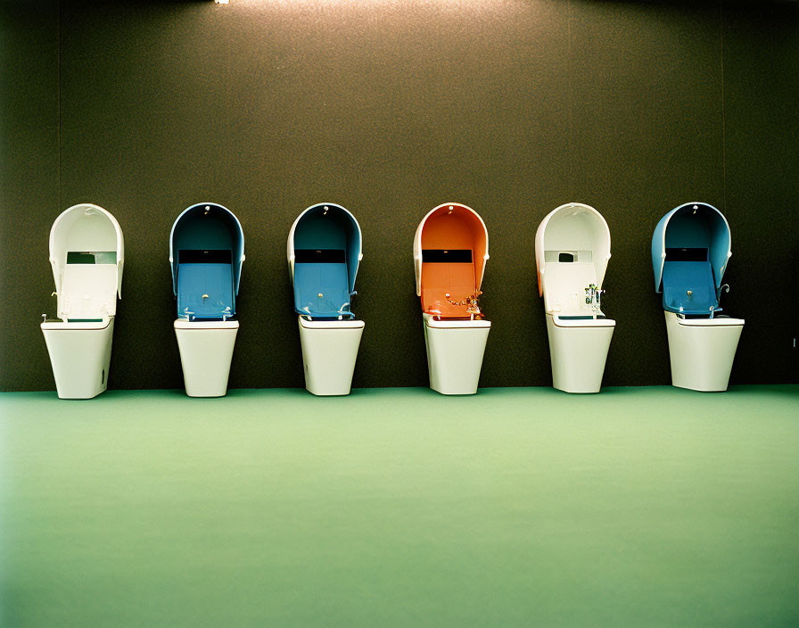 Five white urinals in a row with colorful hoods against a green wall
