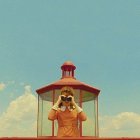 Person in pink blouse gazes at lighthouse under serene blue sky