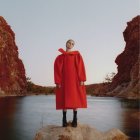 Tranquil scene of woman in red dress by reflective lake