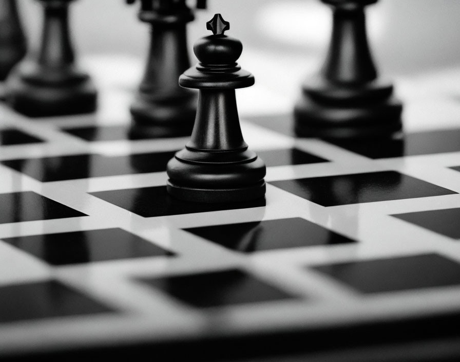 Monochrome photograph of black king chess piece on glossy board