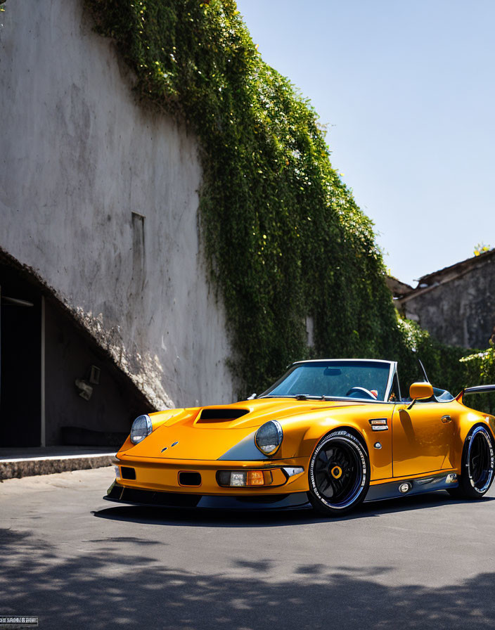 Yellow Sports Car with Black Rims Parked by White Wall with Green Ivy