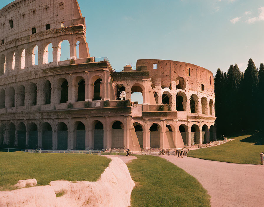 Ancient Roman Colosseum ruins in warm light with clear sky and trees