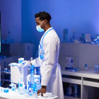 Female pharmacist in mask and lab coat at robotic pharmacy with shelves.