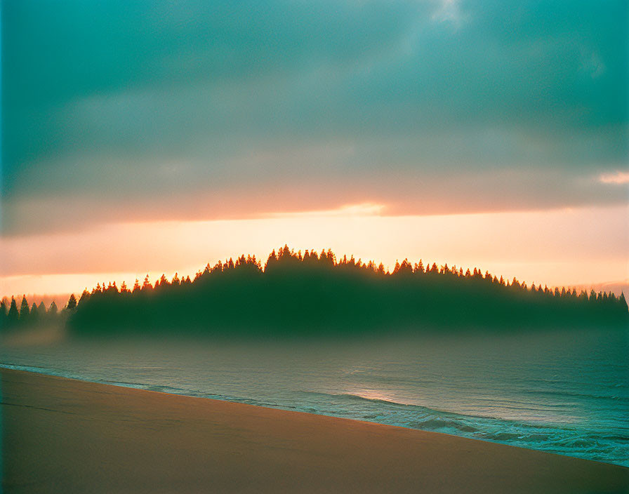 Tranquil beach at dusk with forested island silhouette and calm sea