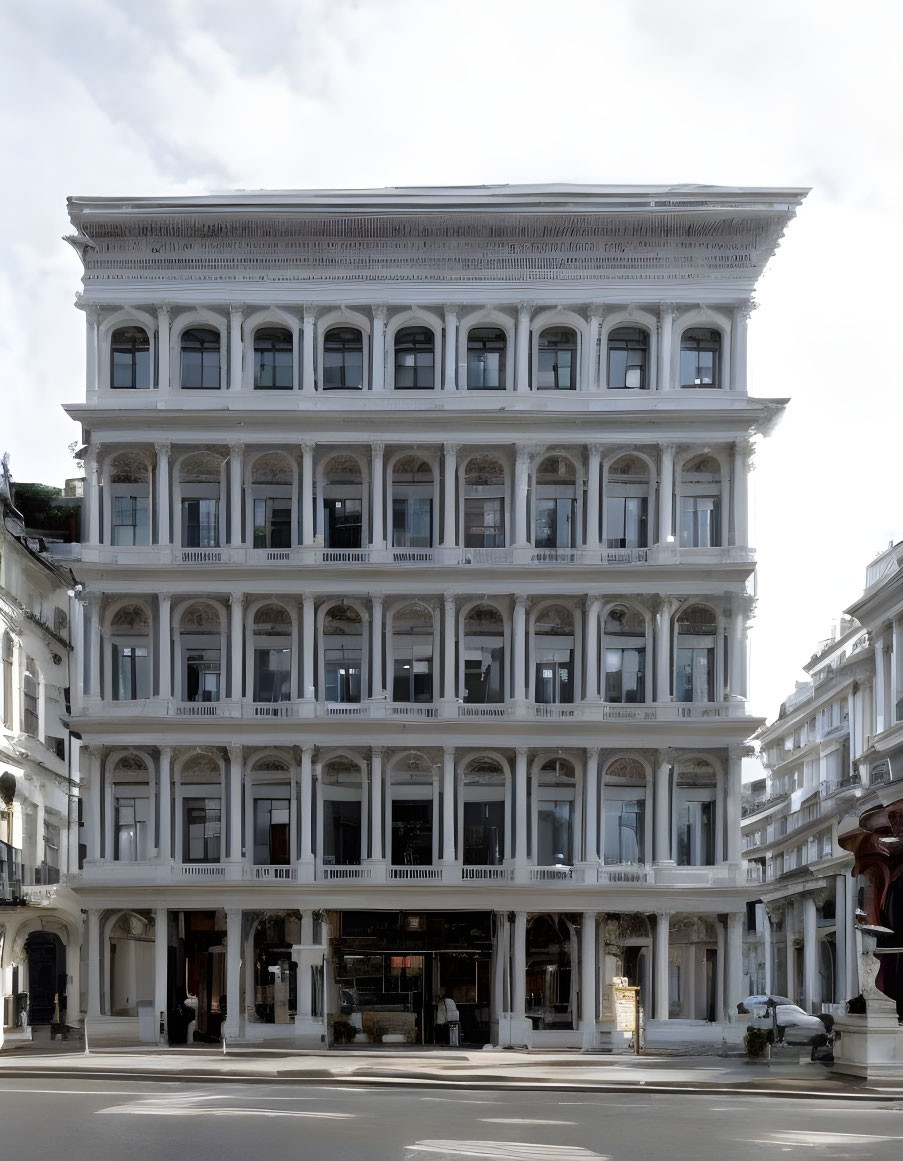 Five-story white building with columns and large windows under clear sky