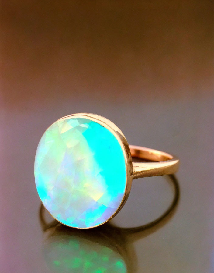 Opalescent gemstone gold ring on pinkish-brown backdrop