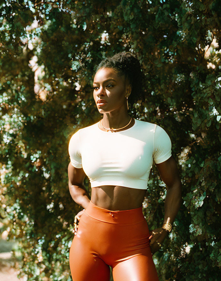 Athletic woman posing outdoors in sunlight.