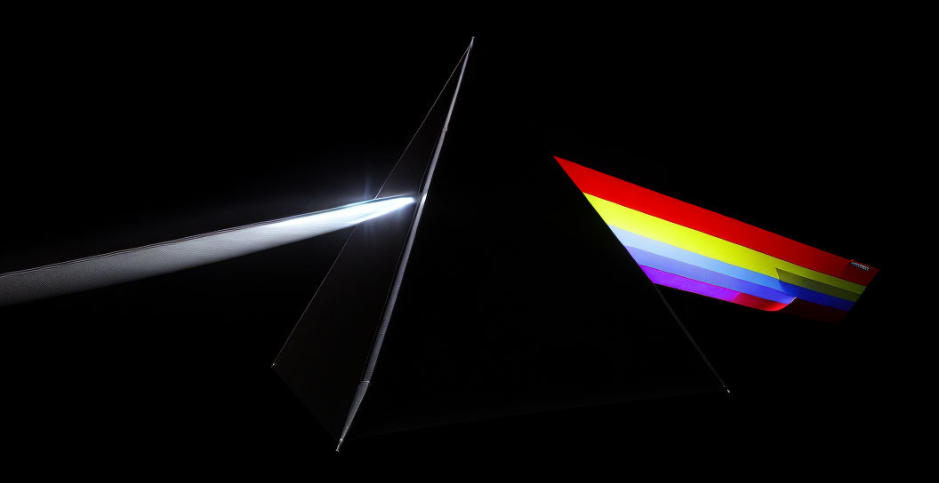 Two open laptops with rainbow wallpaper on one, set against a black background