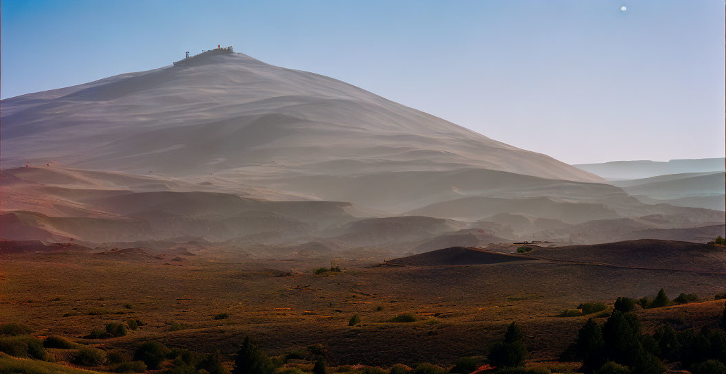 Desert landscape with large sand dune and structure on top