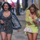 Two women in blue and green cloaks walking in the rain with intricate dresses.