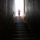 Person ascending futuristic staircase with reflective walls.