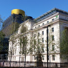 European-style buildings with ornate facades in soft sunlight, surrounded by lush trees and birds under clear