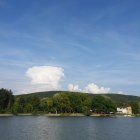 Scenic lake view with houses, mountains, and smoke plume