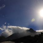 Airplane flying over rugged mountains under starry sky and shining sun.