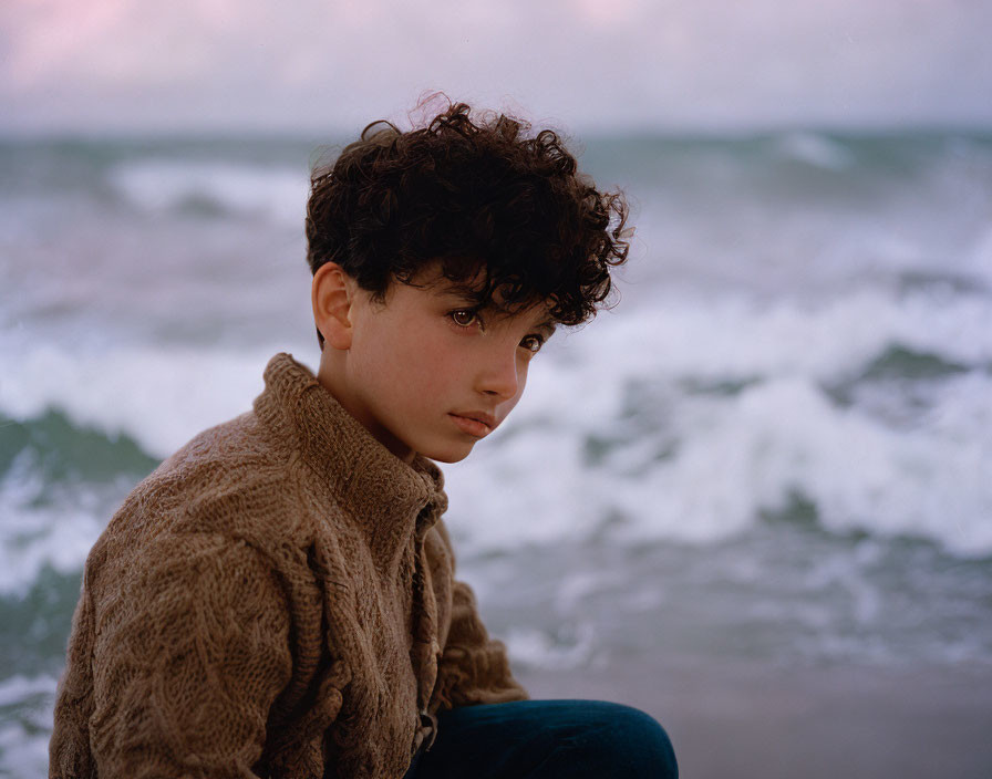 Curly-Haired Person in Knitted Sweater Sitting by the Sea