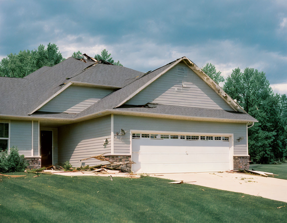 Suburban House with Damaged Roof and Debris After Storm