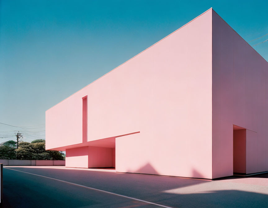 Modern pink building with geometric design under clear blue sky