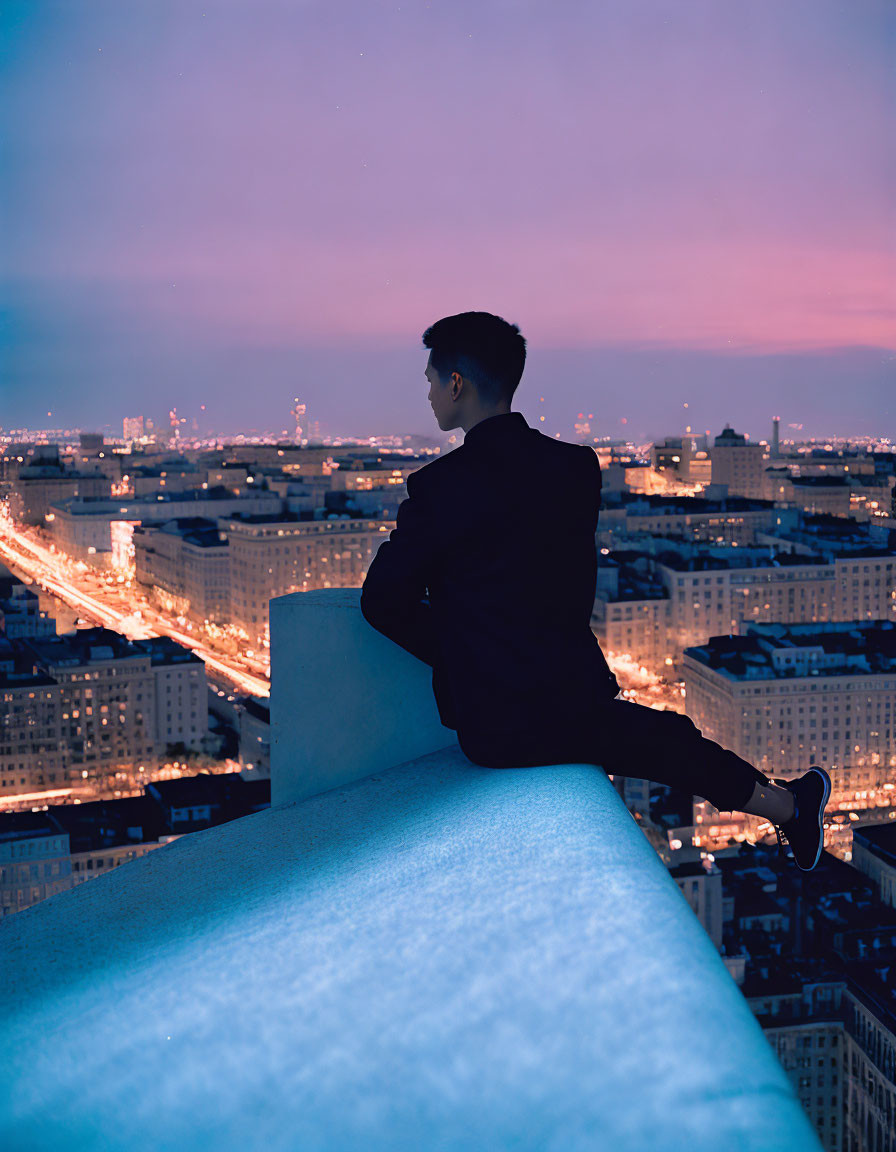 Businessman in suit perched on high ledge above city at dusk