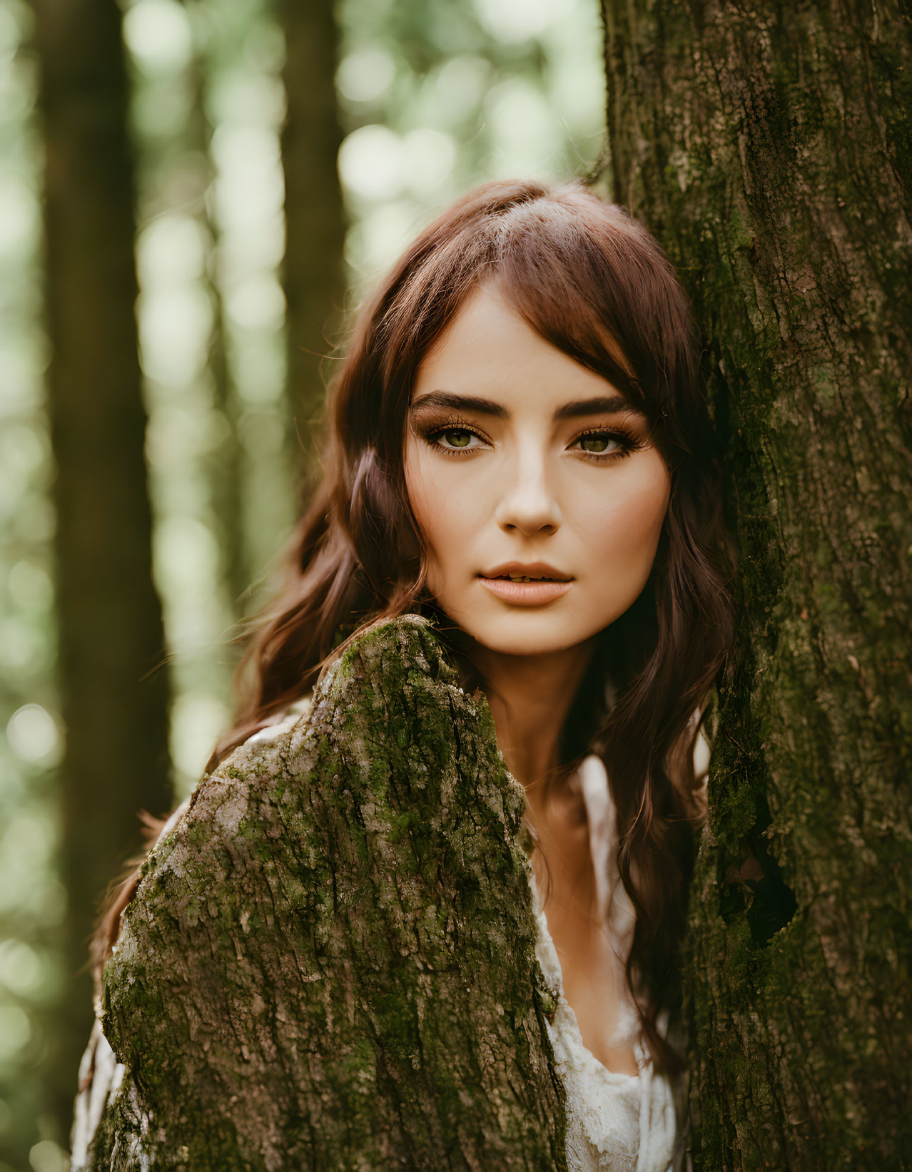 Brown-haired woman in lace dress peeking from forest tree