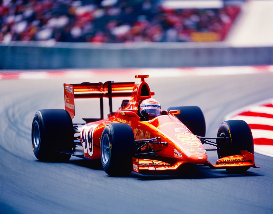 Red Formula 1 race car speeding on racetrack with blurred grandstands