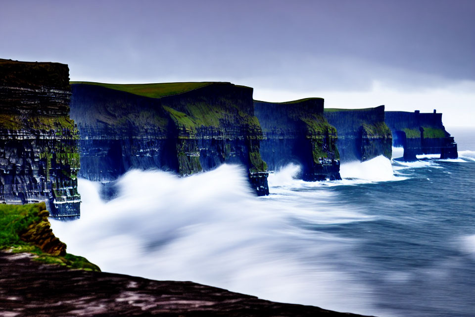 Majestic dark cliffs under stormy sky with crashing waves