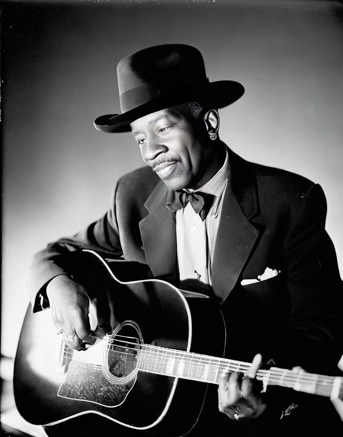 Smiling man in suit playing acoustic guitar