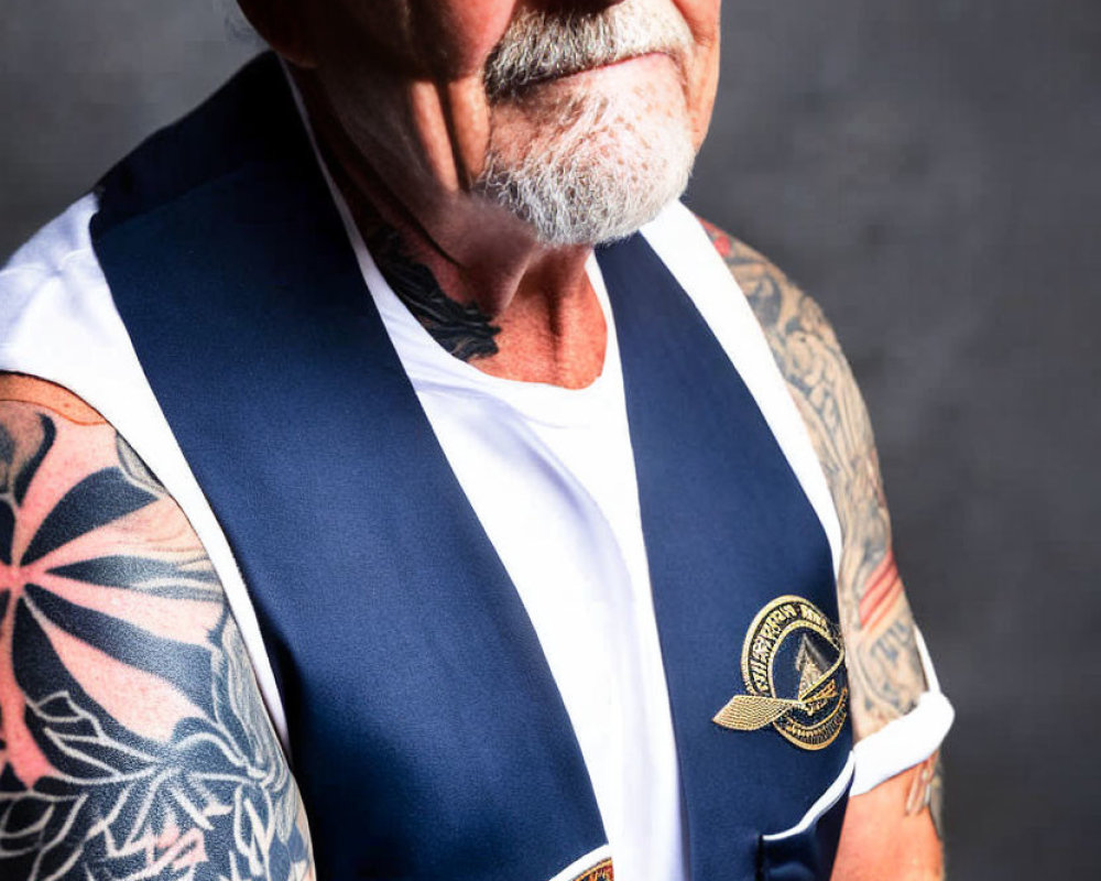 Elderly man with gray beard and arm tattoos in sleeveless vest