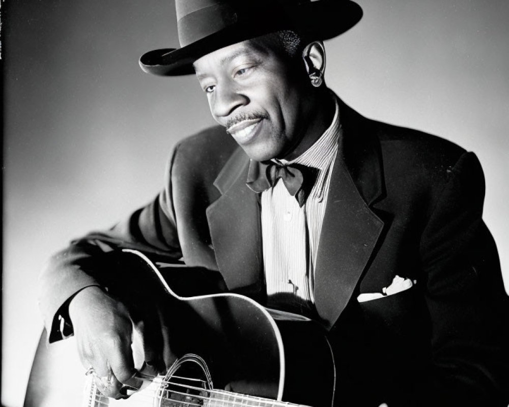 Smiling man in suit playing acoustic guitar