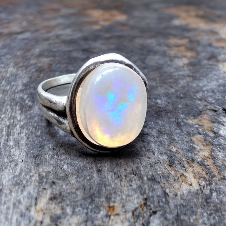 Opalescent gemstone in vintage silver ring on weathered wooden surface