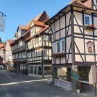 Medieval street scene with period clothing, carts, and cobblestone roads