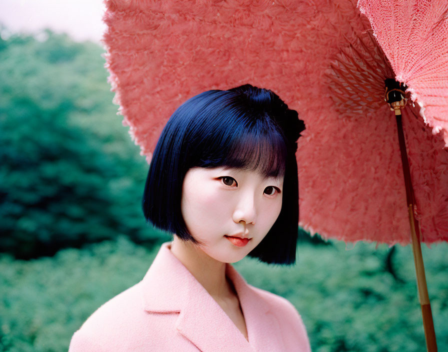 Person with Bob Haircut Under Pink Umbrella in Pink Coat on Green Background