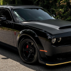 Black Muscle Car Parked on Snowy Ground with Pine Trees Background